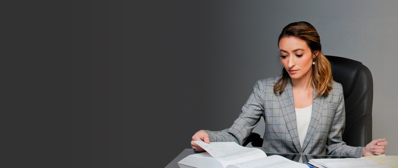 businesswoman in a gray plaid suit, sitting at a desk and reading documents.