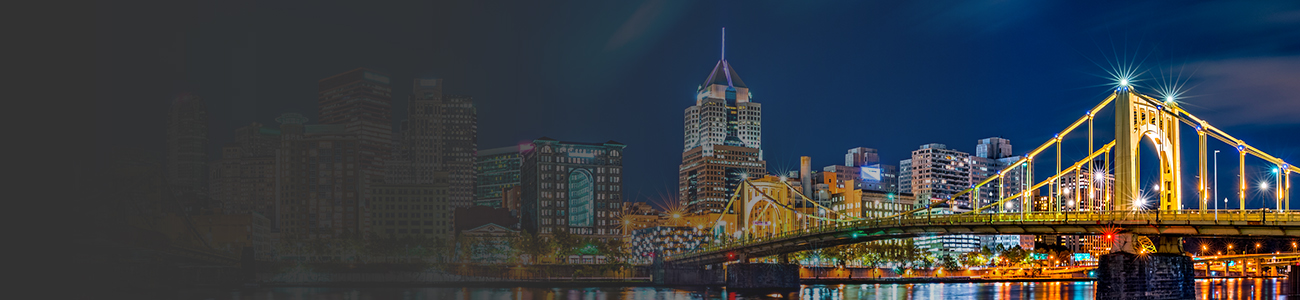 A brightly lit bridge and cityscape at night, reflecting on the water.