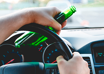 a-person-holding-a-green-bottle-while-driving.jpg